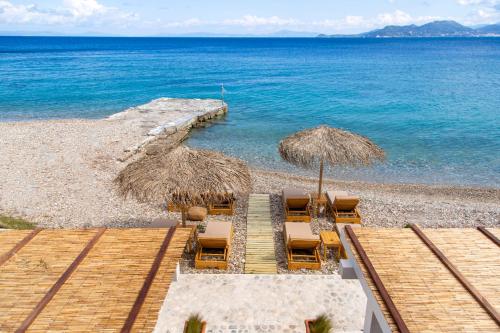 a beach with chairs and umbrellas and the ocean at Aegean Stories pelagos suites in Avlákia