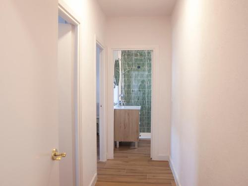 einen Flur mit einem Bad mit einem Waschbecken und einer Tür in der Unterkunft Sanlucarsun Apartamento frente al mar in Sanlúcar de Barrameda