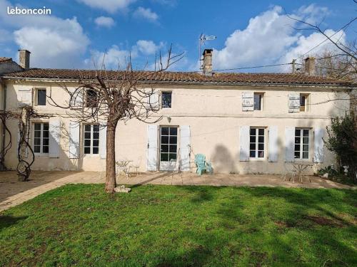 une grande maison blanche avec un arbre devant dans l'établissement ex domaine Chandelier appartement, à Anglade