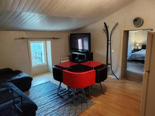 - un salon avec une table rouge et une télévision dans l'établissement ex domaine Chandelier appartement, à Anglade