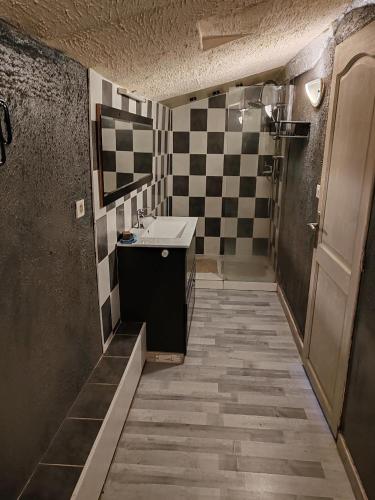 La salle de bains est pourvue d'un lavabo et d'un mur en damier. dans l'établissement ex domaine Chandelier appartement, à Anglade
