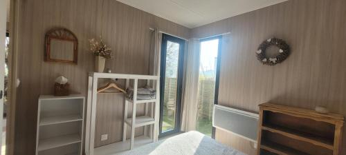 1 dormitorio con estantería blanca y ventana en "La cabane du sentier", logement original en bois et sur pilotis avec beau jardin et très proche de la mer, en Sangatte