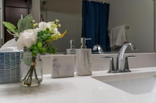 eine Badezimmertheke mit einer Vase aus Blumen und einem Waschbecken in der Unterkunft Corporate Housing by MGM in West Dundee