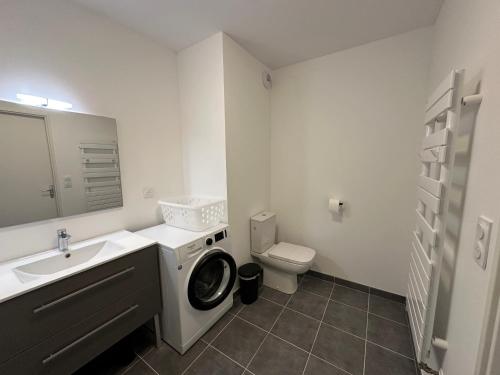 une salle de bain avec une machine à laver et un lavabo dans l'établissement L'émeraude, à Cancale