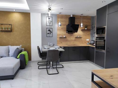 eine Küche und ein Wohnzimmer mit einem Tisch und einem Sofa in der Unterkunft Apartman Aranyhal City in Sárvár