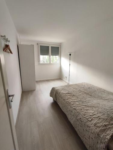 a white bedroom with a bed and a window at Grand F4 avec belle vue in Saint-Étienne