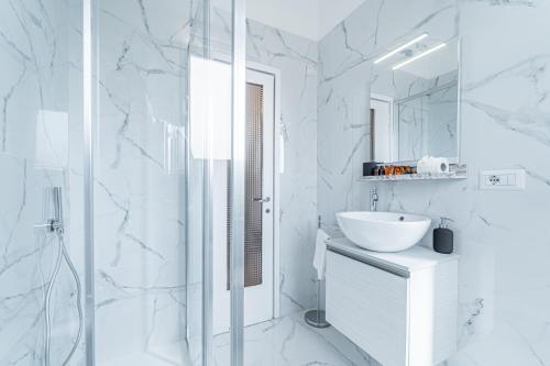a white bathroom with a sink and a mirror at BandeNereSuite Attico in Milan
