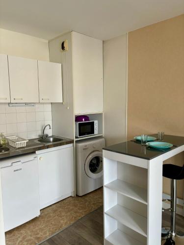 une cuisine avec des armoires blanches et une laveuse et une sécheuse dans l'établissement Charmant studio tours nord, à Tours