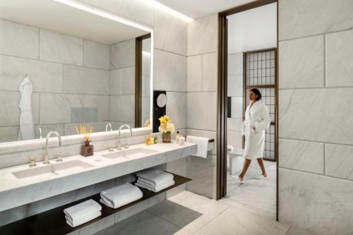 a woman in a bathroom with two sinks and a mirror at Hotel Cafe Royal in London