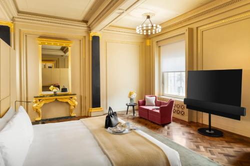 a room with a bed and a tv and a chair at Hotel Cafe Royal in London