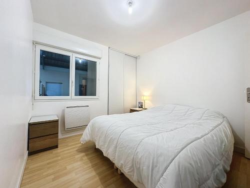 une chambre blanche avec un lit et une fenêtre dans l'établissement Le Semaphore T2 proche mer, terrasse, balcon, à Landéda