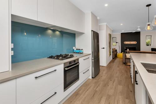 a kitchen with white cabinets and a blue wall at Seaside Escape - Ruakaka Holiday Home in Ruakaka