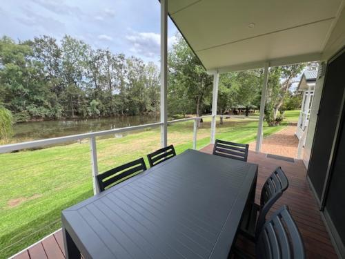 a table and chairs on a porch with a view of a river at Denman Van Village in Denman