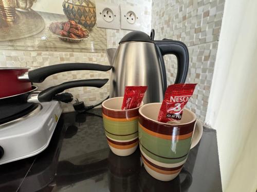 two cups sitting on a counter with a tea kettle at Casablanca Central Suites - Casa Port in Casablanca