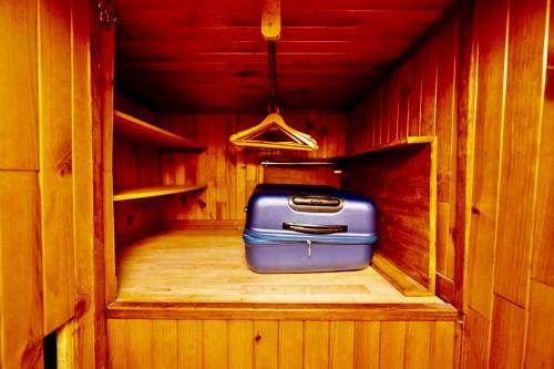 une valise bleue assise à l'intérieur d'une cabine en bois dans l'établissement Sublime Studio - Centré & Tout Equipé, à Grenoble