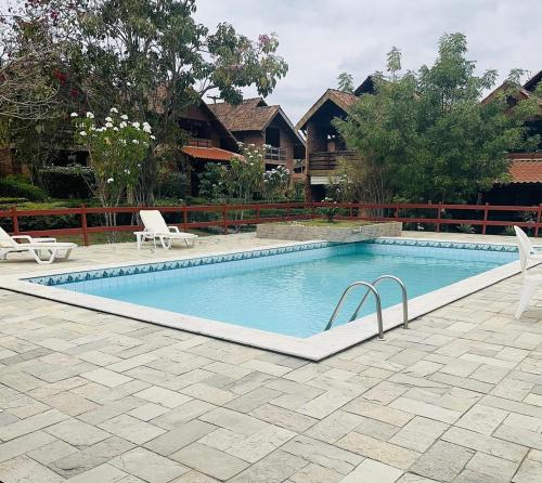 a swimming pool with two chairs next to a house at Casa de Campo em Gravatá super aconhegante in Gravatá