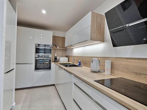 une cuisine avec des armoires blanches et un comptoir dans l'établissement Le Bonheur Charmant *Disney*Paris*RER A*, à Bussy-Saint-Georges