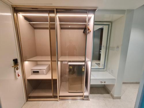 a glass cabinet with a microwave and a mirror at Luxury Hotel Tumkur in Tumkūr