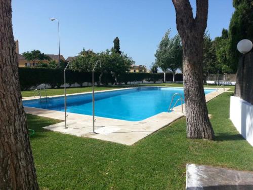 una piscina en un parque con dos árboles en Áncora Costa en El Puerto de Santa María