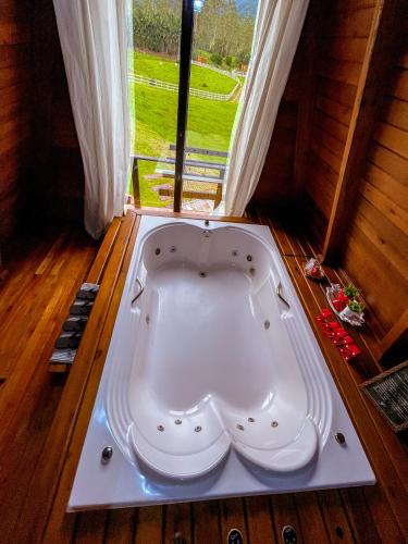 a bath tub in a room with a window at Morada do Corujão - Aconchego in Praia Grande