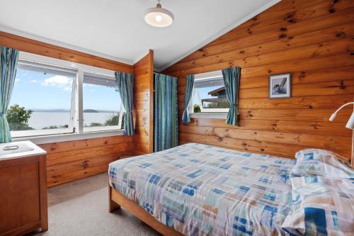 - une chambre avec des murs en bois, un lit et des fenêtres dans l'établissement Te Moe - Lake Taupo Holiday Home, à Turangi