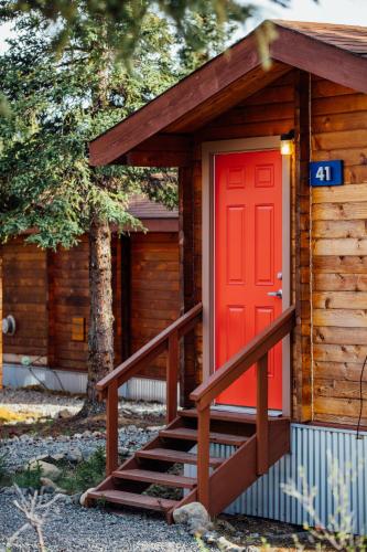 a small cabin with a red door and stairs at Denali Cabins in McKinley Park