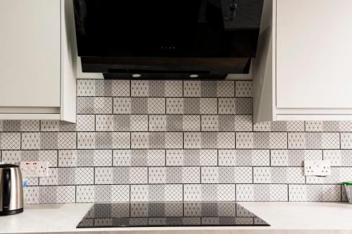 a kitchen with black and white tile on the wall at Luxurious London Studios in Harrow