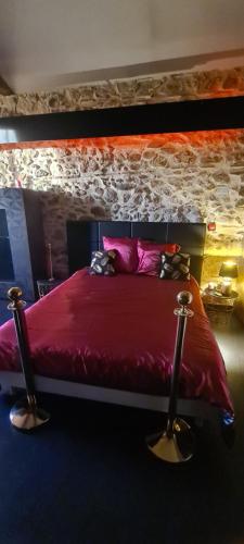 a bedroom with a red bed with a stone wall at CHEZ PAM agréable chambre d’hôte pour les amoureux in Marmande