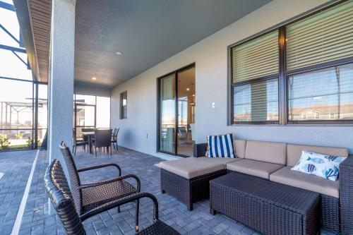 ein Wohnzimmer mit Sofa, Stühlen und Fenstern in der Unterkunft 2957 FS - Luxury Oasis: 6BR Villa Pool Game in Kissimmee