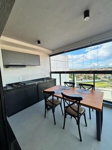 a kitchen with a wooden table and chairs and a large window at Studio 905 in Marília