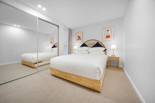 um quarto branco com uma cama e um espelho em Elegant 2-Bed by Lyneham Wetlands near the CBD em Camberra