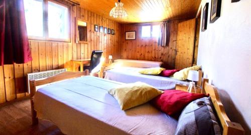 two beds in a room with wooden walls at Chalet Pre Saint-jacques - Chalets pour 15 Personnes 601 in Tignes