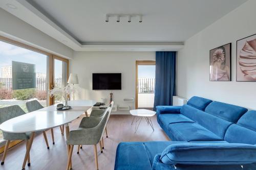 a living room with a blue couch and a table at Welcome Gdańsk Apartments Nadmotławie Gym and Sauna in Gdańsk