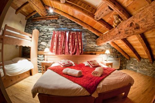 a bedroom with a large bed and a stone wall at Chalet Les Champs Du Pont - Chalets pour 15 Personnes 611 in Tignes
