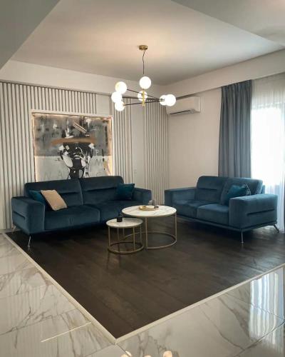 a living room with two blue couches and a table at Penthouse Împăratul Traian in Craiova
