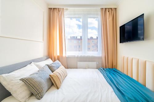 1 dormitorio con 1 cama, TV y ventana en Apartament Przytulny, en Kędzierzyn-Koźle