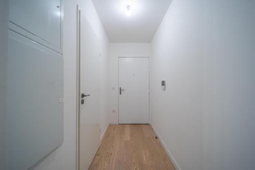 un couloir avec des portes blanches et un plancher en bois dans l'établissement Premium Studio Flat, au Plessis-Robinson