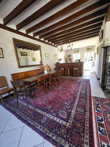 a dining room with a table and chairs on a rug at Domaine de charme - Les Places in Lassay-sur-Croisne