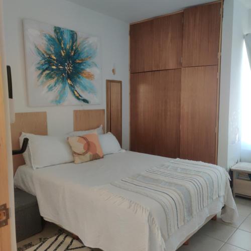 1 dormitorio con cama blanca y cabecero de madera en Agradable departamento para descanso o home office. en Cabo San Lucas