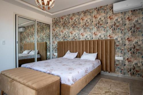 a bedroom with a large bed in a room with floral wallpaper at Villa Dhaouia torki in Kelibia