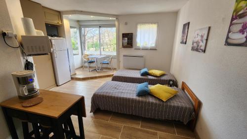 une chambre avec deux lits, une table et une cuisine dans l'établissement Studio Garrigues Gréoux les bains curistes Thalatherme, à Gréoux-les-Bains