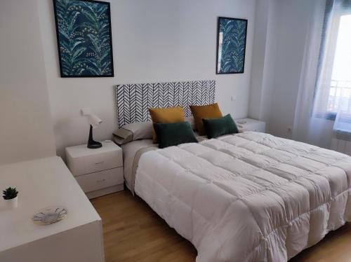 a white bedroom with a large bed and a table at Apartamento Candelaria in Zamora