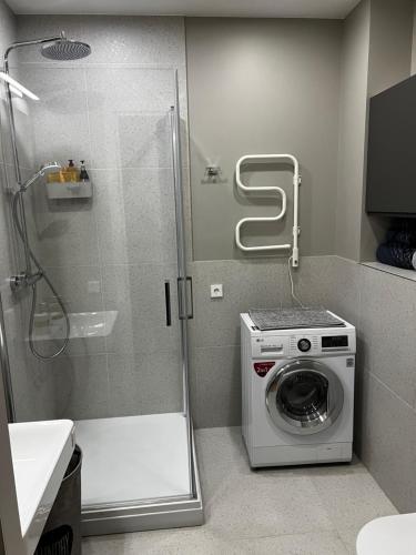La salle de bains est pourvue d'une douche et d'un lave-linge. dans l'établissement Hoffmann Rezidence, à Riga