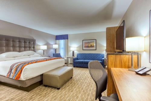 Habitación de hotel con cama y silla azul en Drury Inn and Suites St Louis Collinsville, en Collinsville
