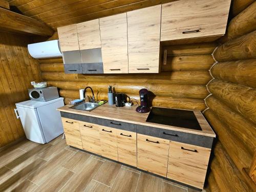 a kitchen with wooden cabinets and a sink in a log cabin at Tóparti Rönkház Vaja in Vaja