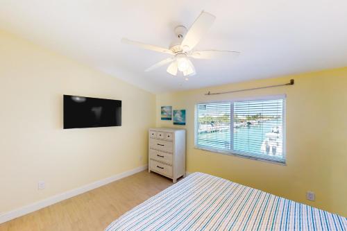 a bedroom with a ceiling fan and a television at KCB Canal Livin' in Key Colony Beach