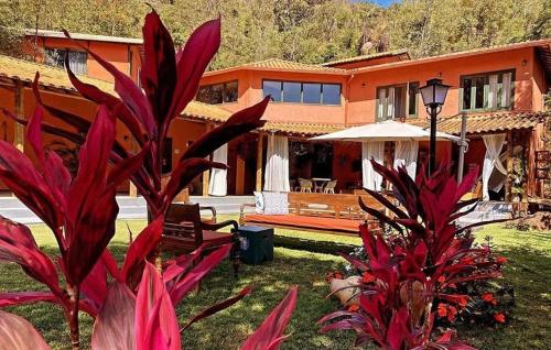 a house with red plants in front of it at Pousada Boutique das Pedras in Moeda