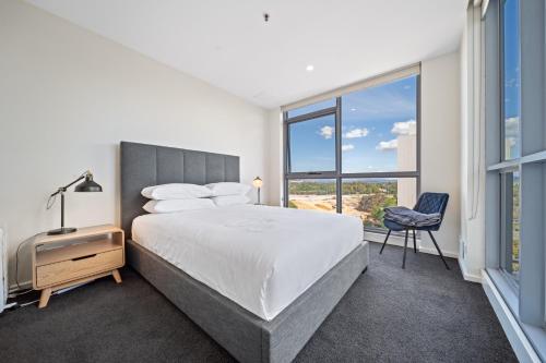 a bedroom with a bed and a chair and a window at Glorious Central Canberra 1-Bed with Pool & Sauna in Canberra