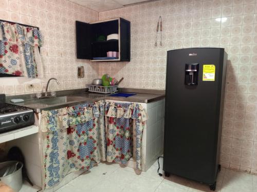 uma cozinha com um frigorífico preto e um lavatório em Mary playas coveñas em Coveñas