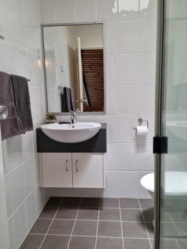 ein weißes Badezimmer mit einem Waschbecken und einem Spiegel in der Unterkunft Whiteoaks Motel & Lodges in Toowoomba